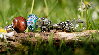 silver bracelet with beads and lock laying on wood on a grass field