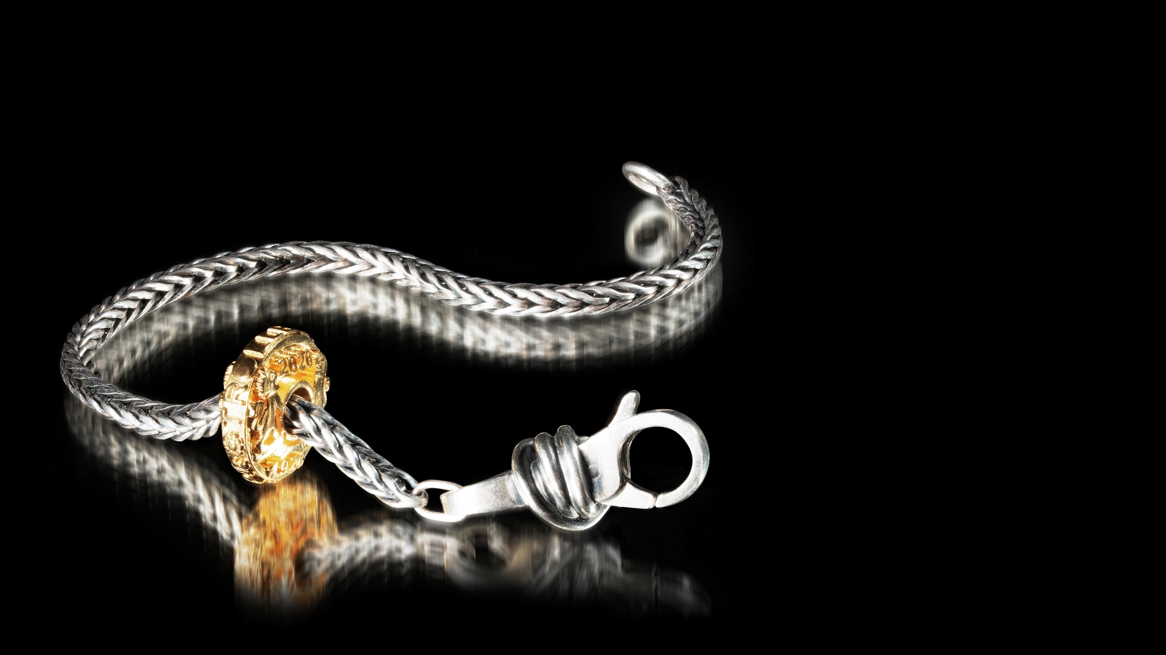 Silver bracelet with a gold clasp on a black background